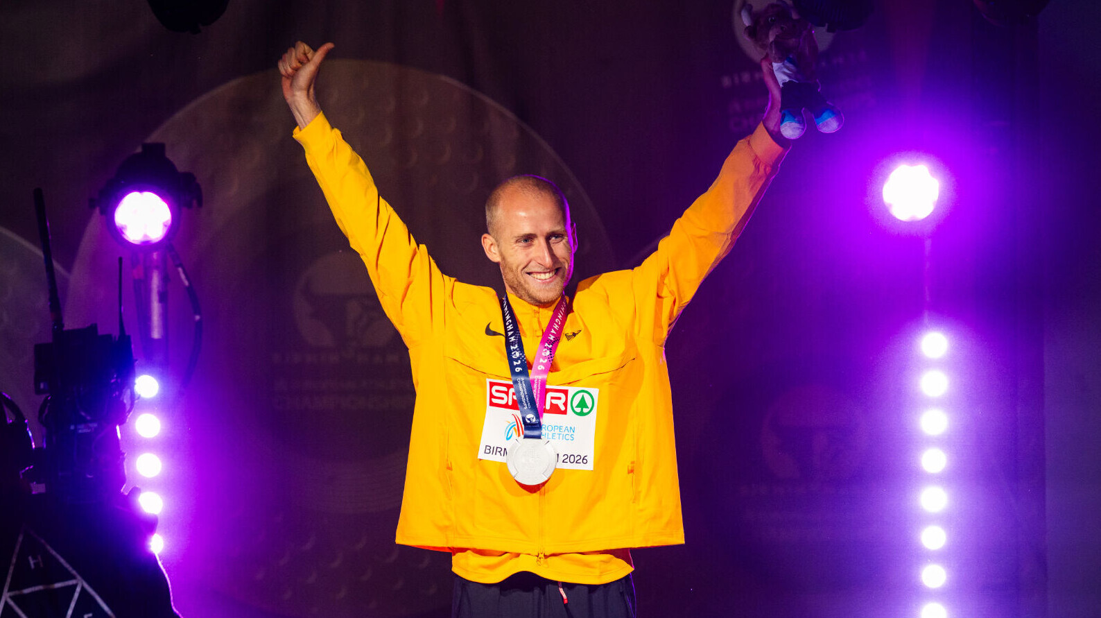 Der deutsche Läufer Florian Bremm streckt jubelnd bei einer Sigerehrung beide Arme in die Höhe und hat dabei eine Silbermedaille um den Hals.