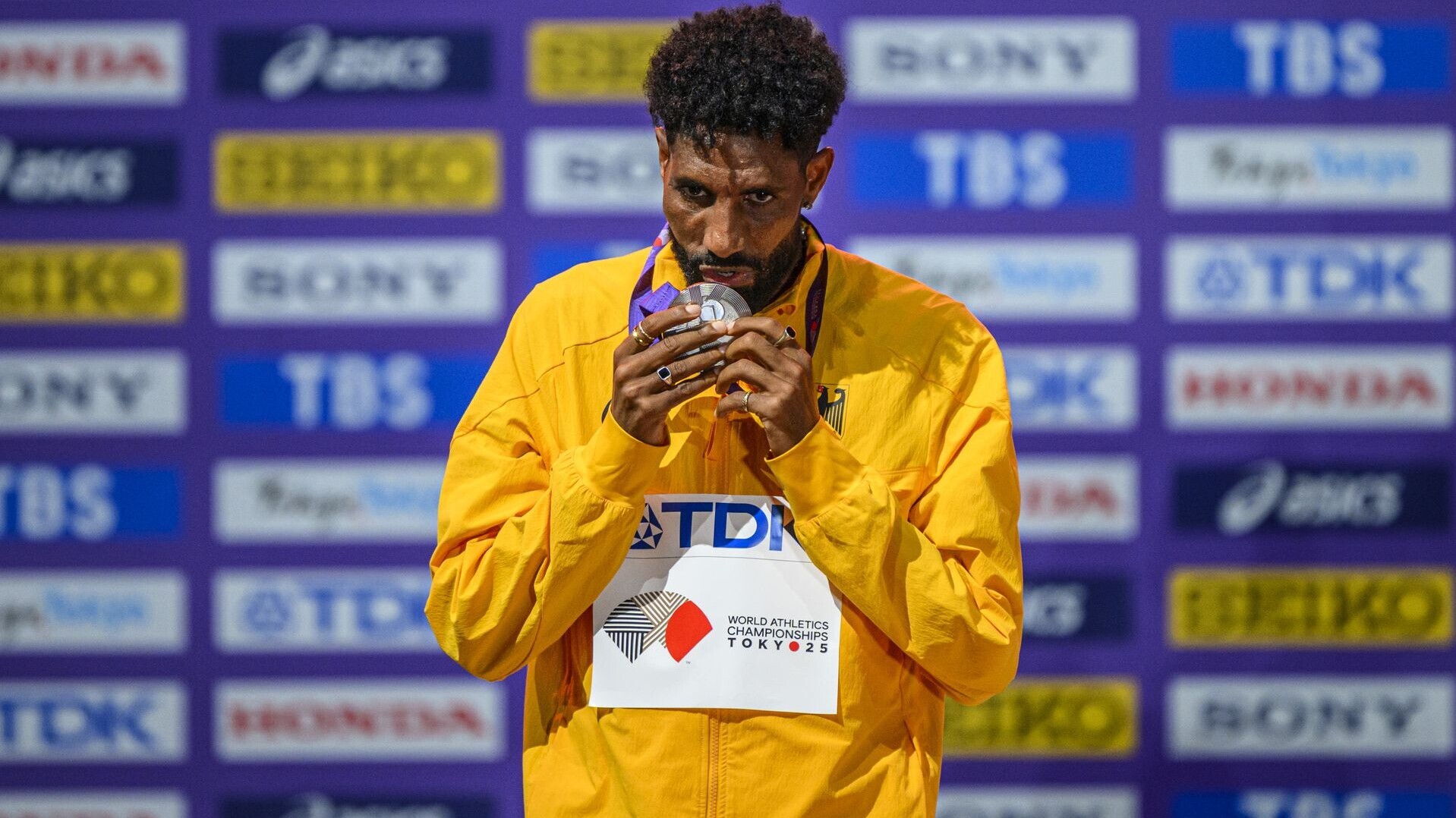 Amanal Petros, im gelben Nationalmannschaftsoutfit, küsst auf dem Podium seine WM-Medaille