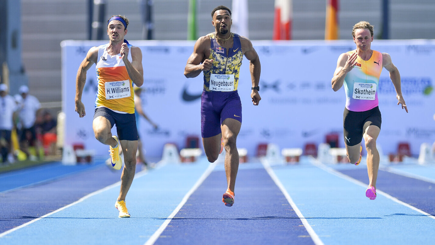 Fünf Leichtathleten sprinten auf einer blauen Laufbahn nebeneinander Richtung Ziel.