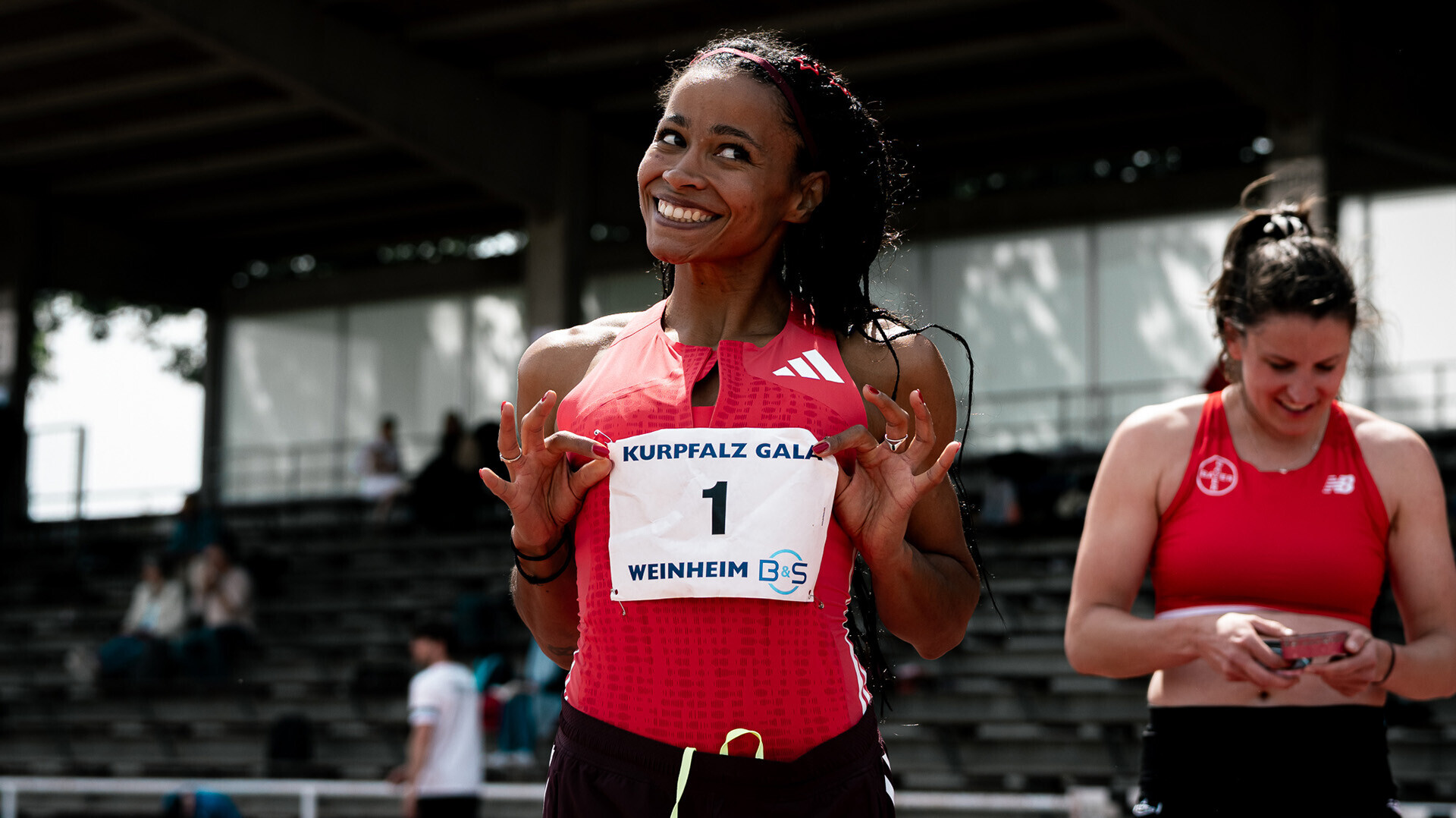 Weitspringerin Jazmin Sawyers präsentiert lächelnd ihre Startnummer mit der Nummer 1. 