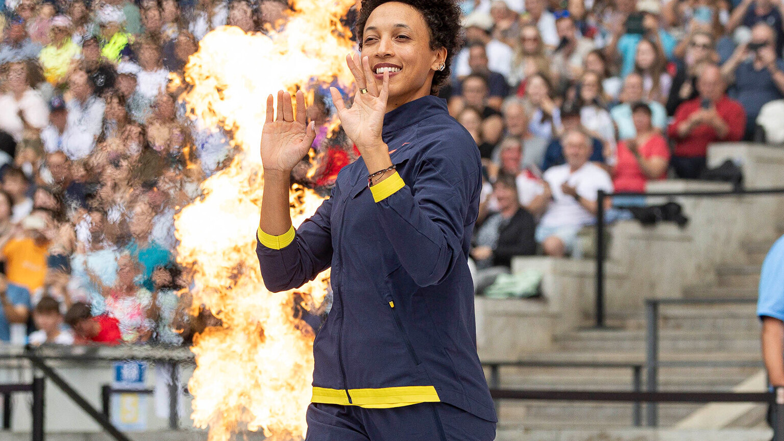 Malaika Mihambo betritt winkend bei Feuerfontänen das Stadion