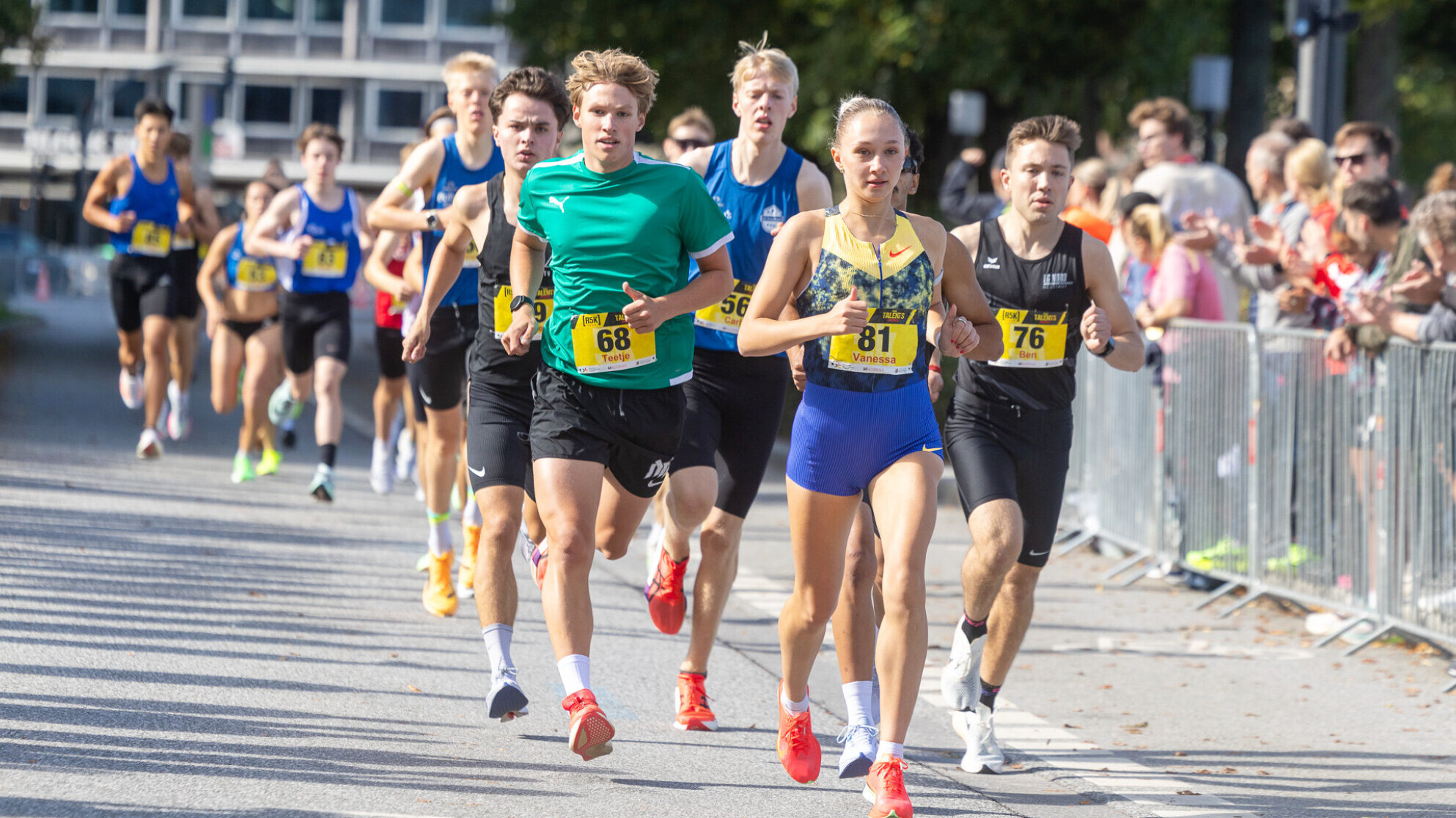 Die deutsche Läuferin Vanessa Mikitenko führt ein Straßenrennen vor einer Gruppe männlicher Läufer an.