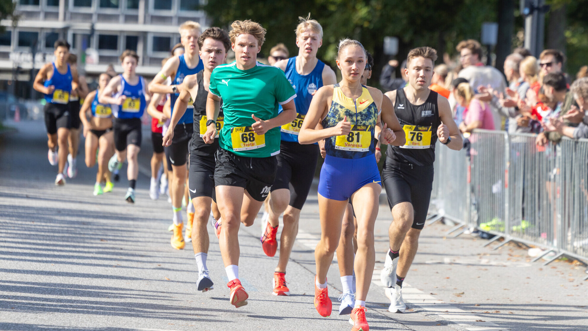 Die deutsche Läuferin Vanessa Mikitenko führt ein Straßenrennen vor einer Gruppe männlicher Läufer an.