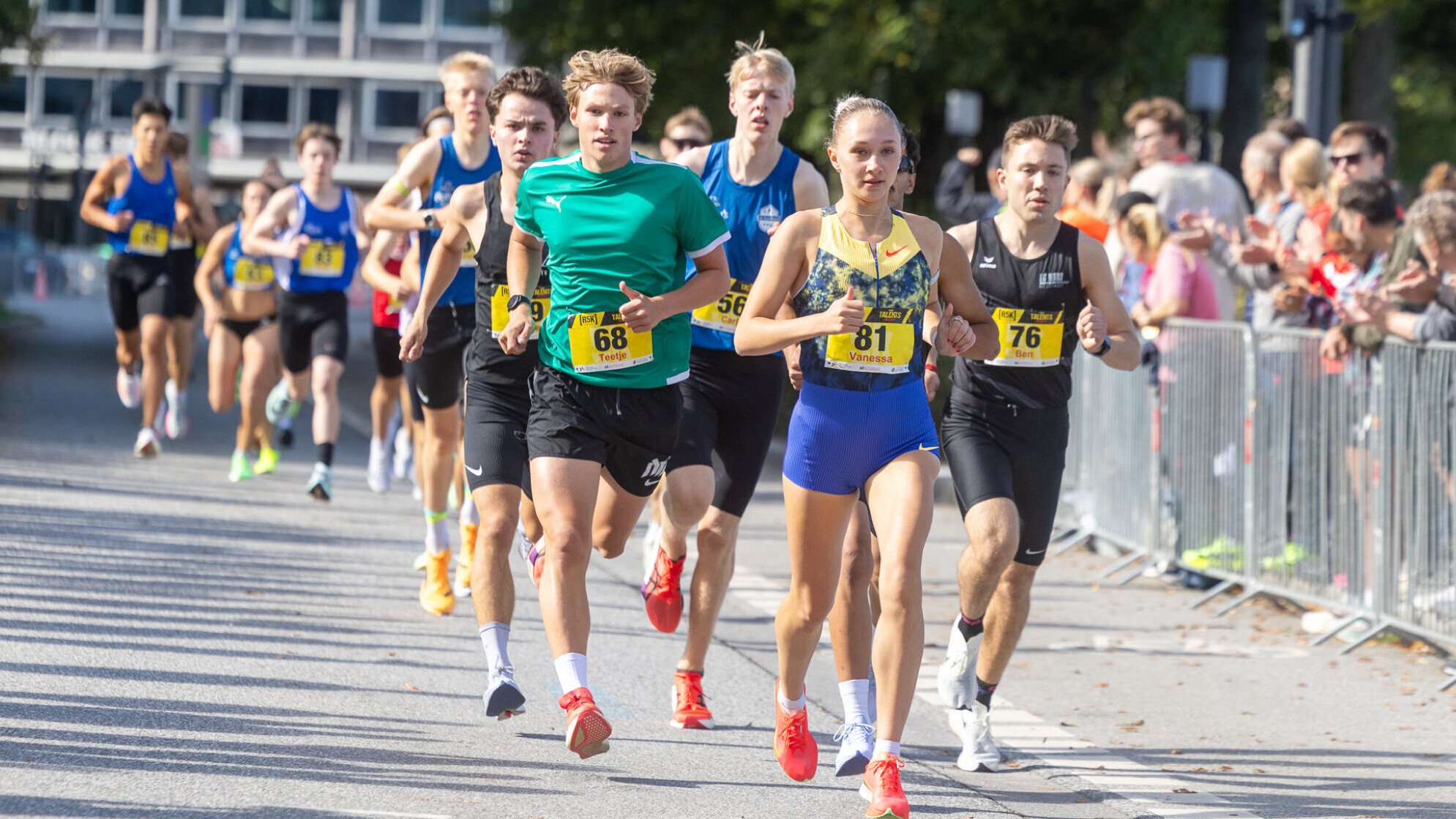 Die deutsche Läuferin Vanessa Mikitenko führt ein Straßenrennen vor einer Gruppe männlicher Läufer an.