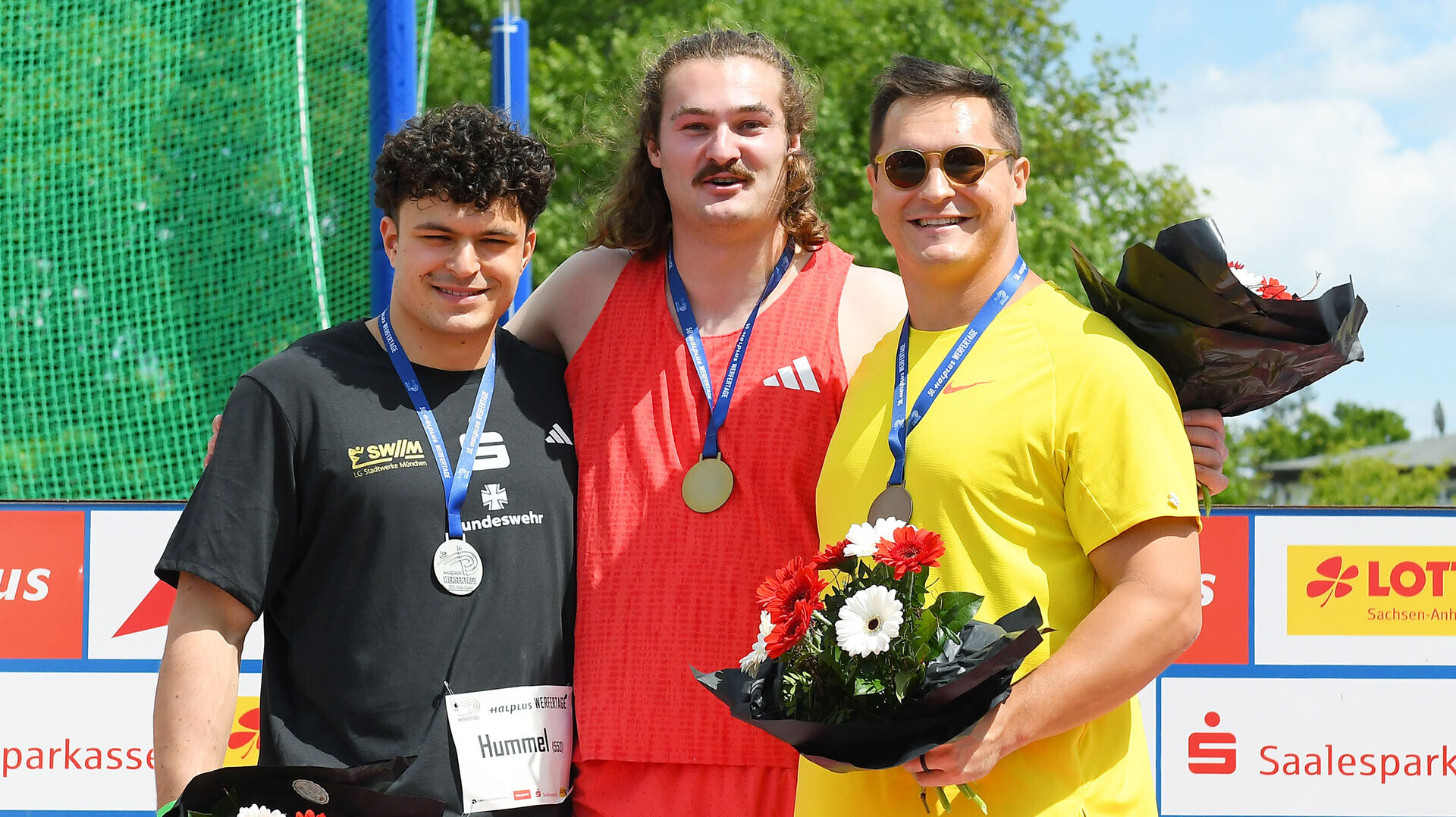 Merlin Hummel (Platz zwei), Ethan Katzberg (Platz eins) und Rudy Winkler (Platz drei) stehen zusammen auf einem Podium. Alle haben eine Medaille um den Hals, Rudy Winkler trägt eine Sonnenbrille. 