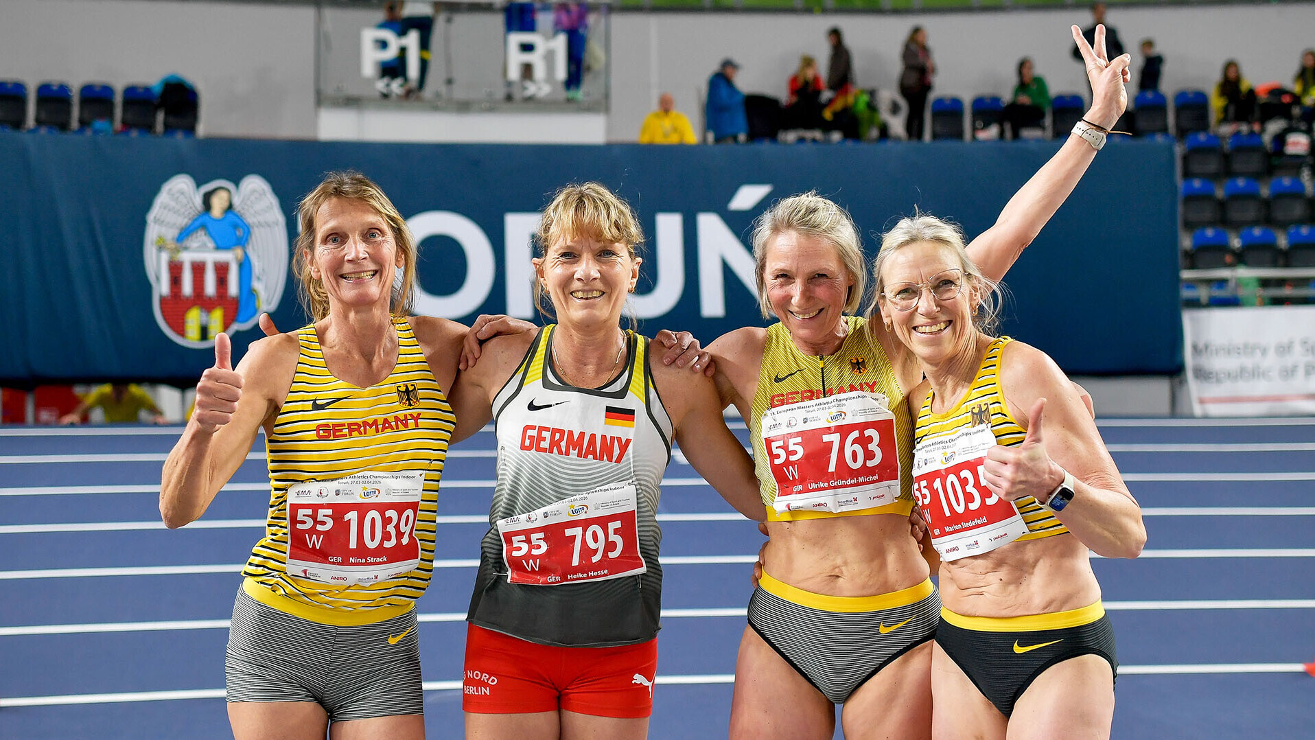 Vier Athletinnen posieren Arm in Arm