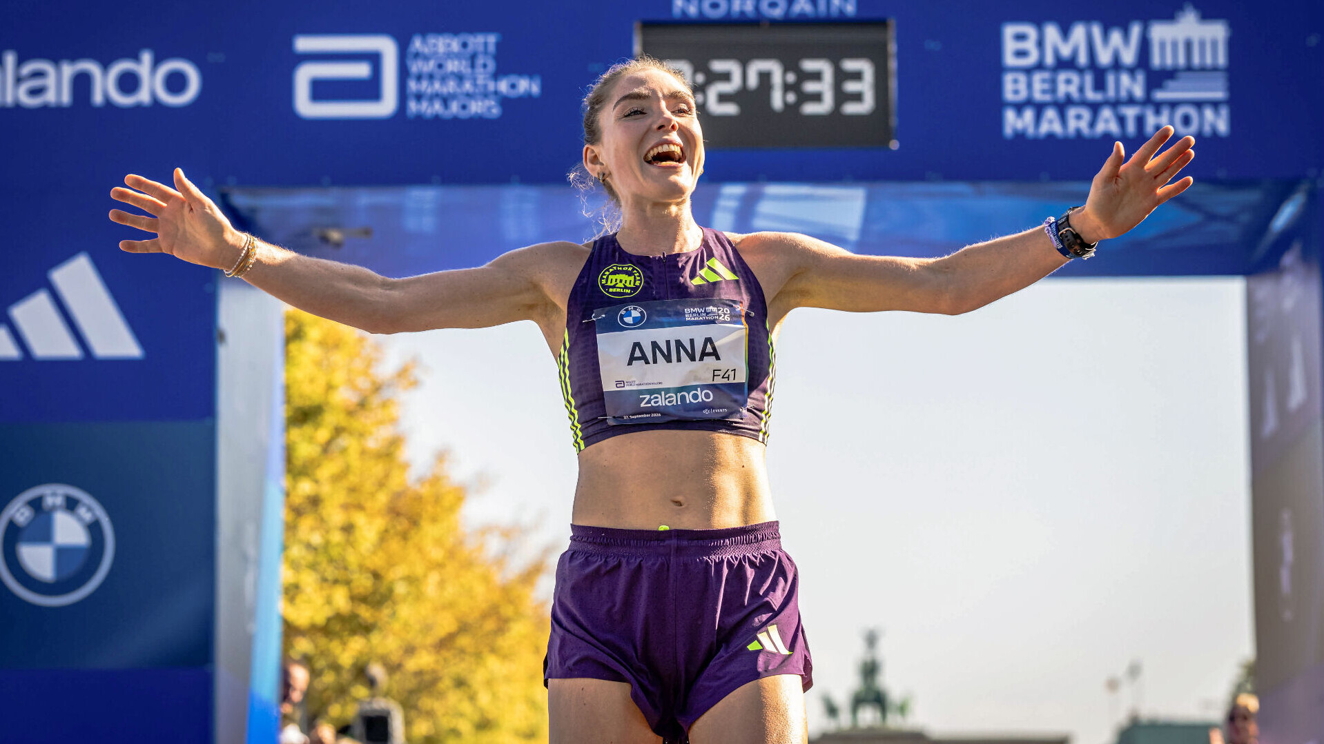 Die deutsche Läuferin jubelt im Zielbereich des Berlin-Marathon 2026. Dabei lacht sie und breitet die Arme aus.