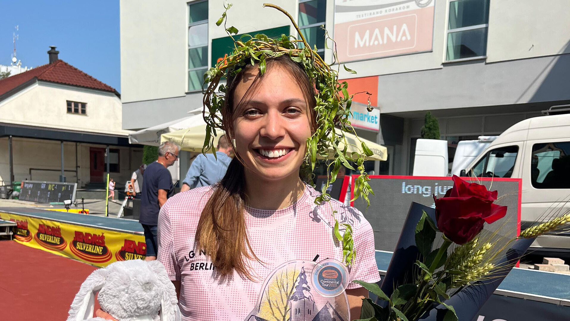 Porträt von Dreispringerin Caroline Joyeux mit Blumen und einem Maskottchen in der Hand und einem Kranz auf dem Kopf