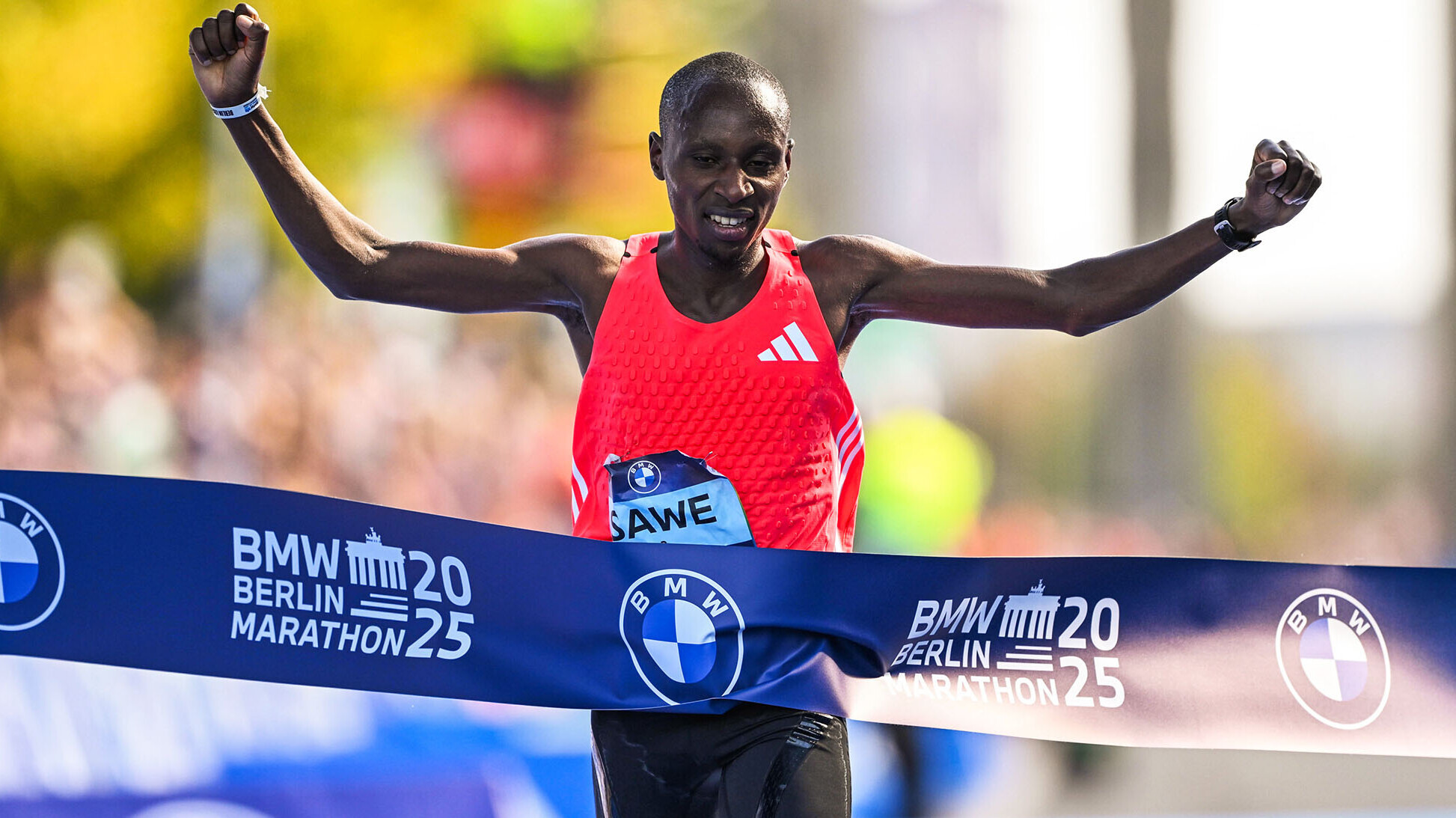 Sabastian Sawe läuft jubelnd über das Zielband, auf dem "BMW Berlin Marathon" zu lesen ist