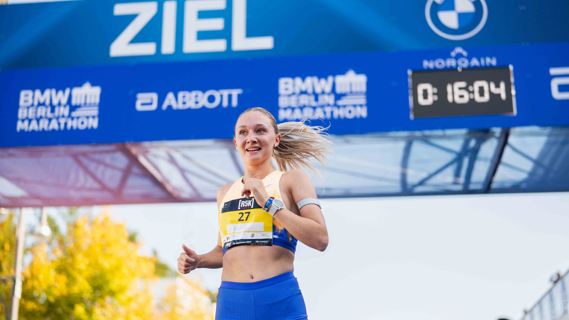 Die deutsche Langstrecklerin Vanessa Mikitenko läuft lächeld durch einen Zielbogen ins Ziel.