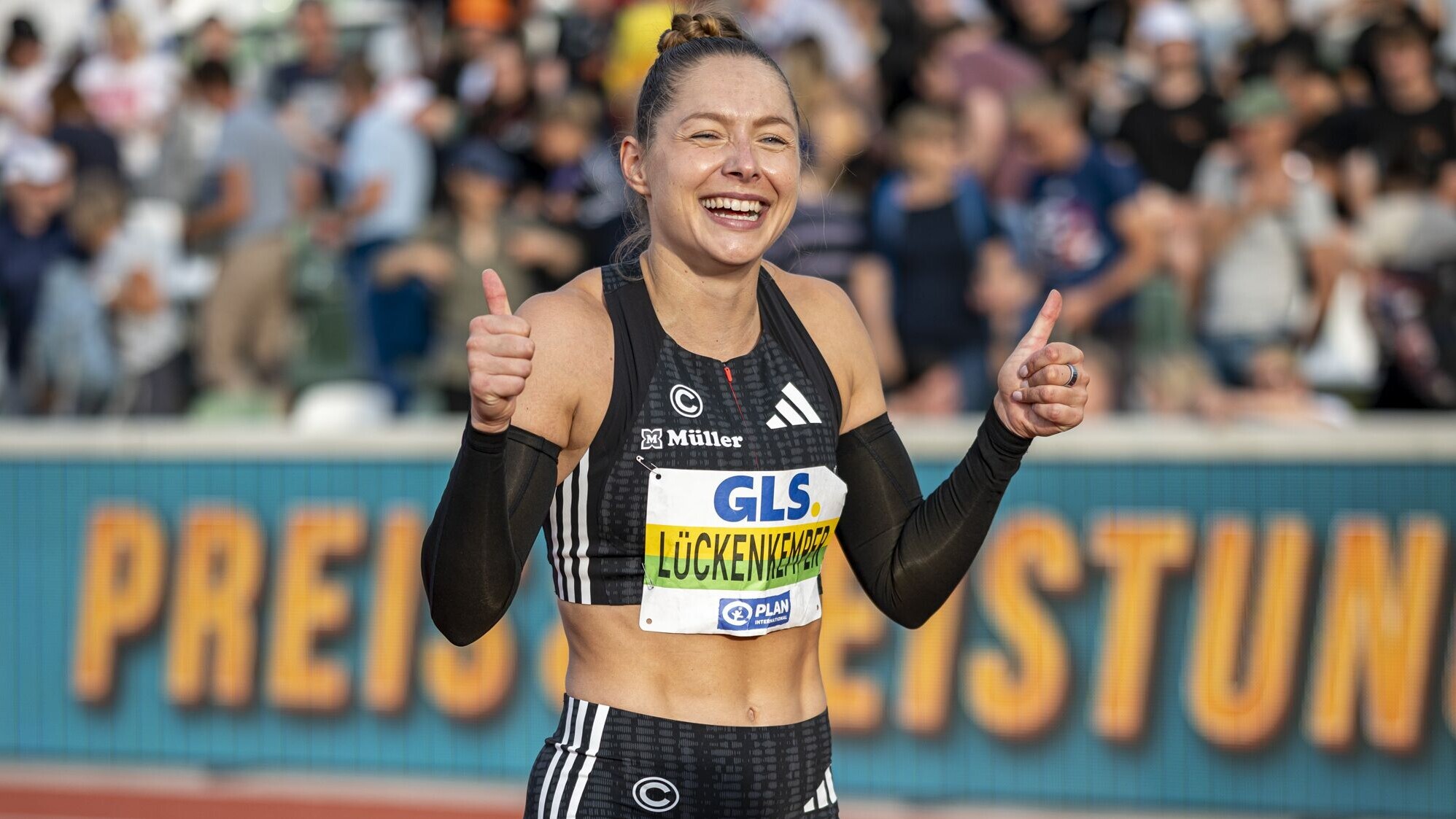 Gina Lückenkemper reckt strahlend beide Daumen nach oben. 