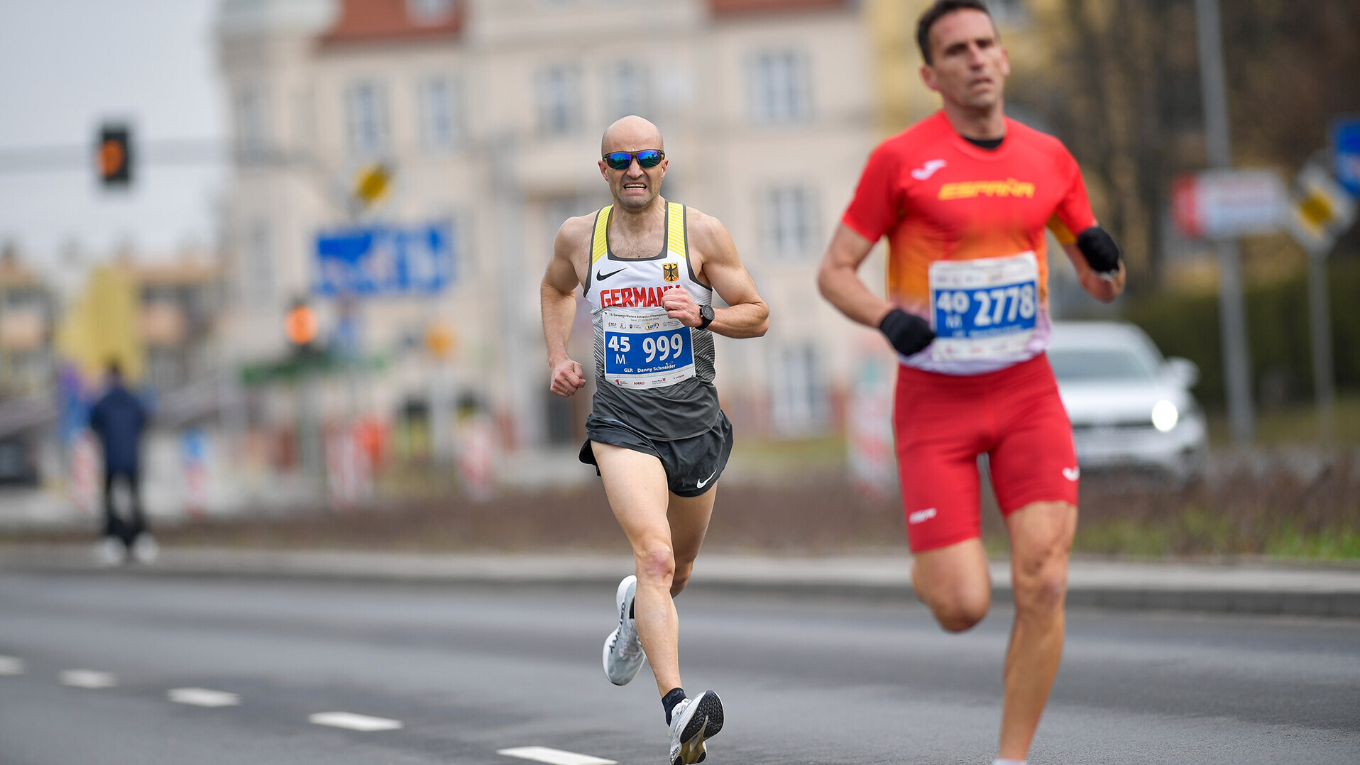 Danny Schneider läuft mit Sonnenbrille auf der Straße hinter einem Spanier