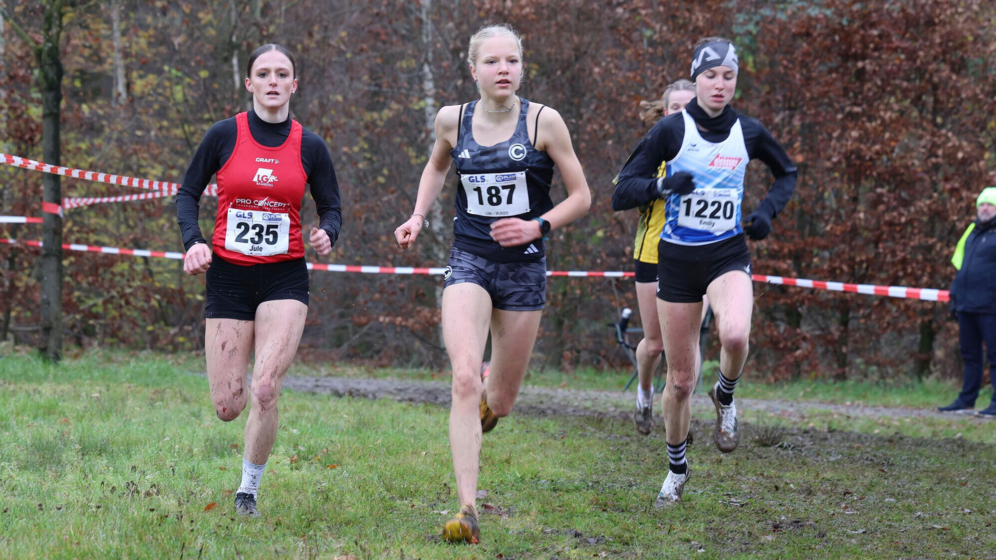 Jule Lindner, Ada Werner und Emily Junginger laufen über das Gras, im Hintergrund die Absperrung der Strecke