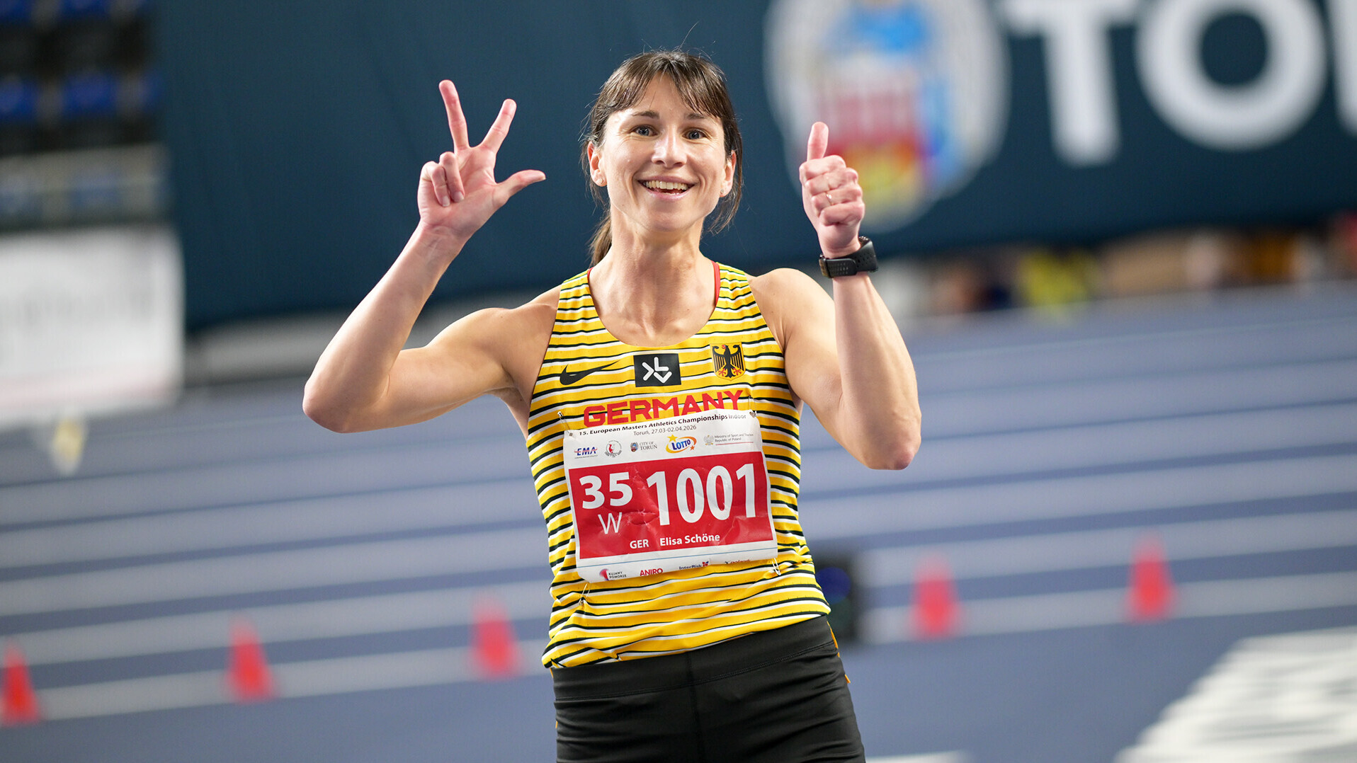 Elisa Schöne zeigt mit der einen Hand drei Finger, mit der anderen den Daumen nach oben