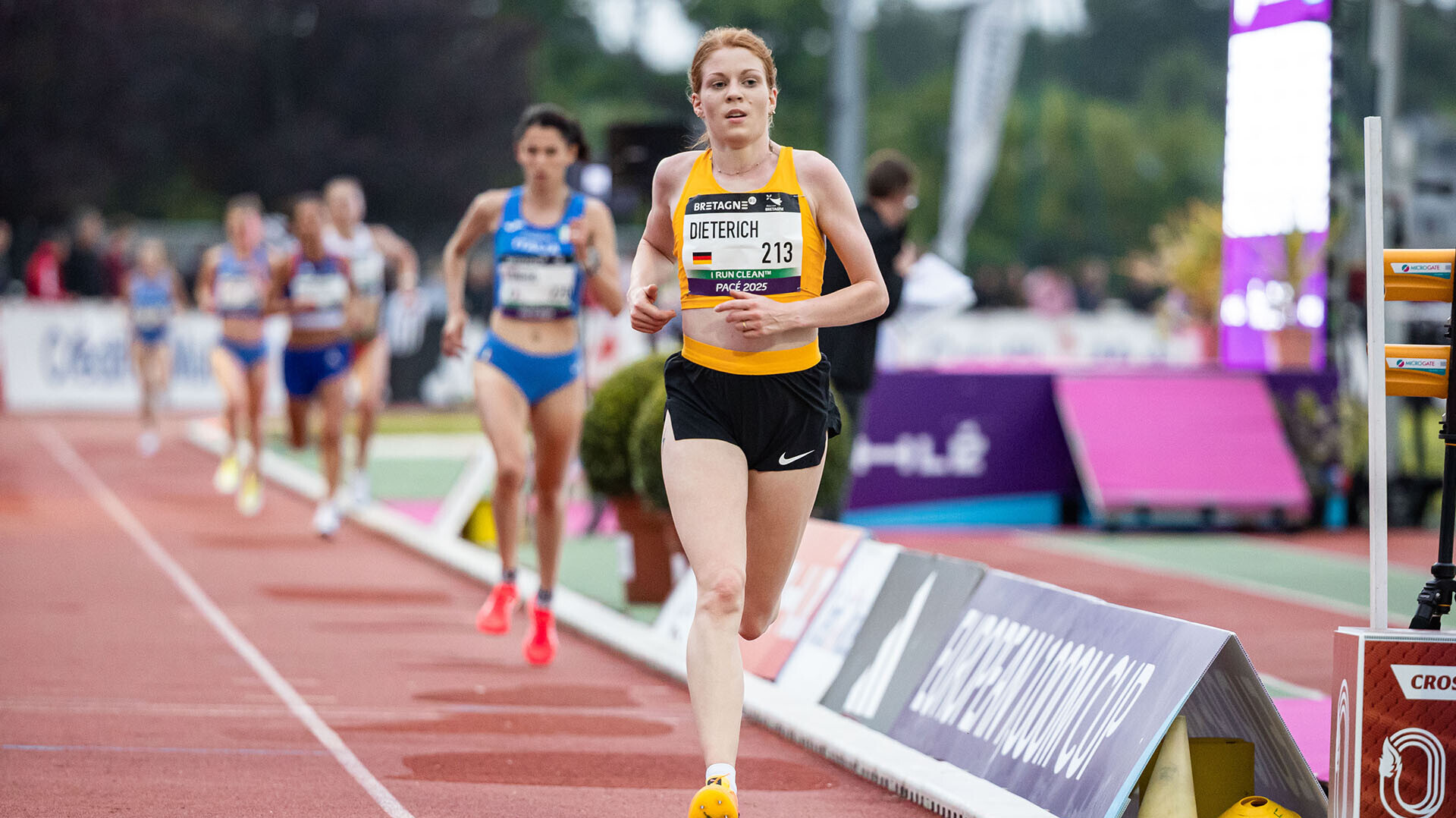 Eva Dieterich läuft im gelben Nationaltrikot beim Europacup in Pacé, im Hintergrund einige weitere Läuferinnen. 