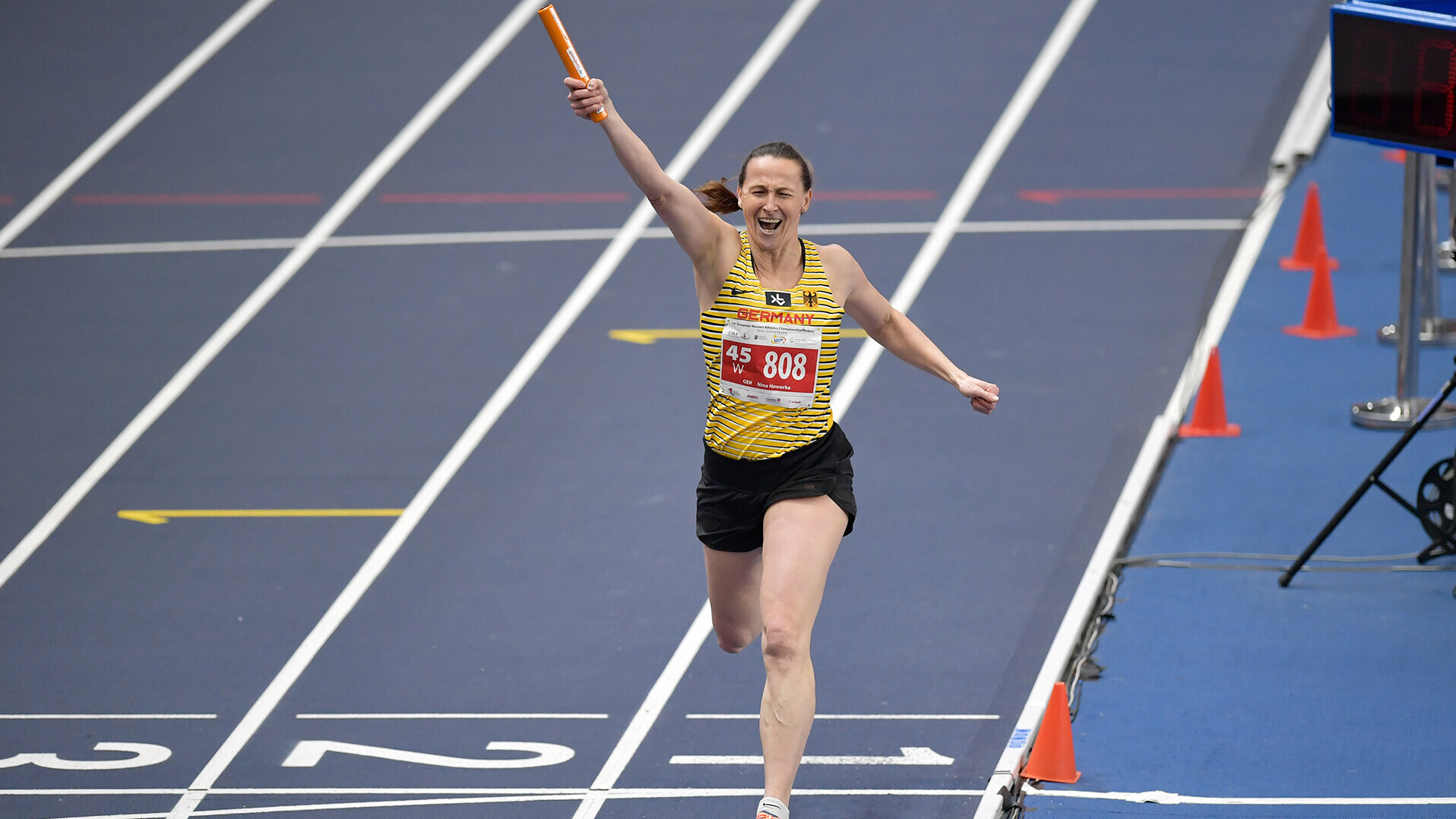 Nina Howorka läuft über die Ziellinie und reckt den rechten Arm mit Staffelstab in die Luft