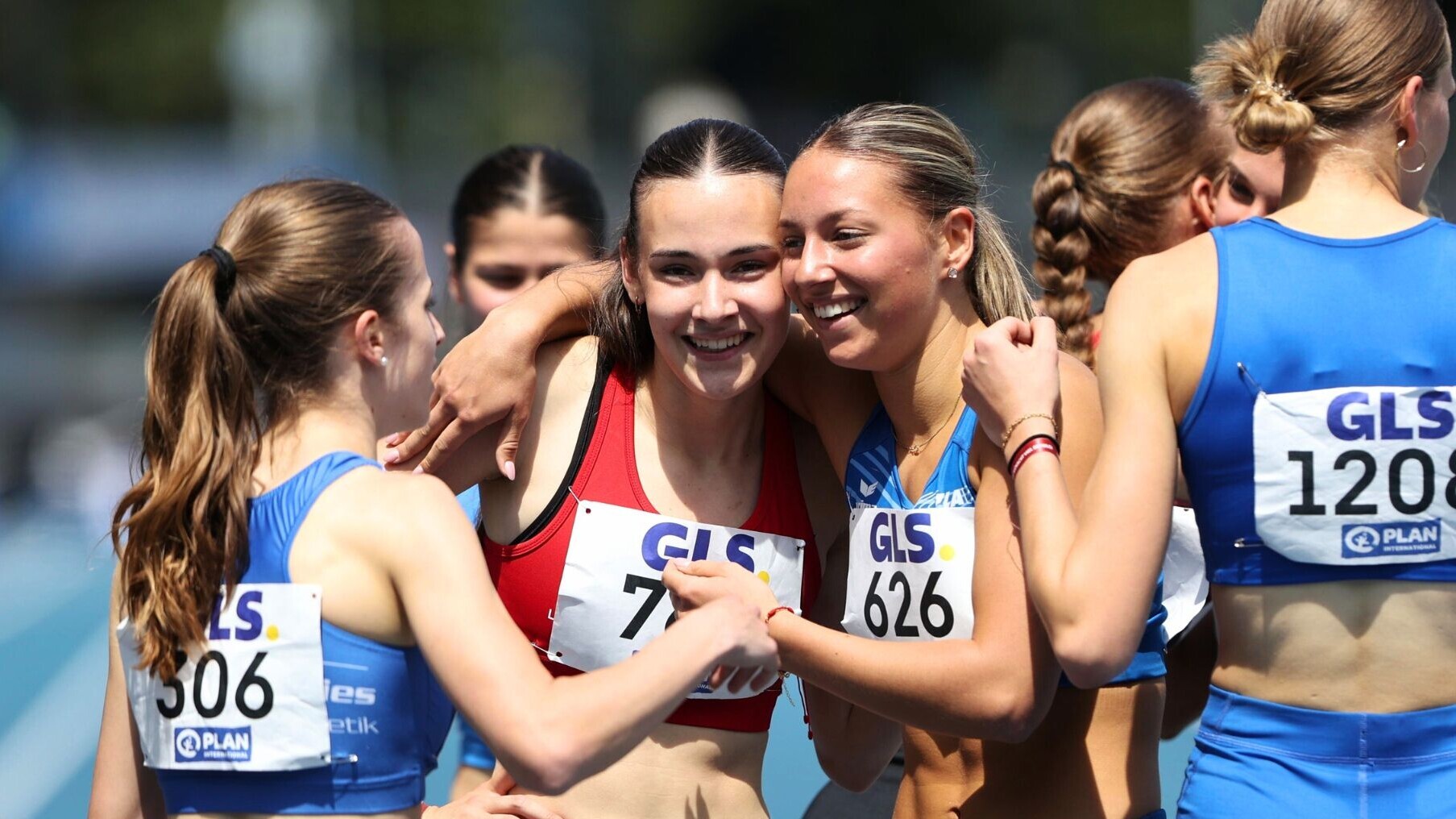 400-Meter-Läuferinnen stehen als Gruppe zusammen und beglückwünschen sich mit Handschlägen und Umarmungen.