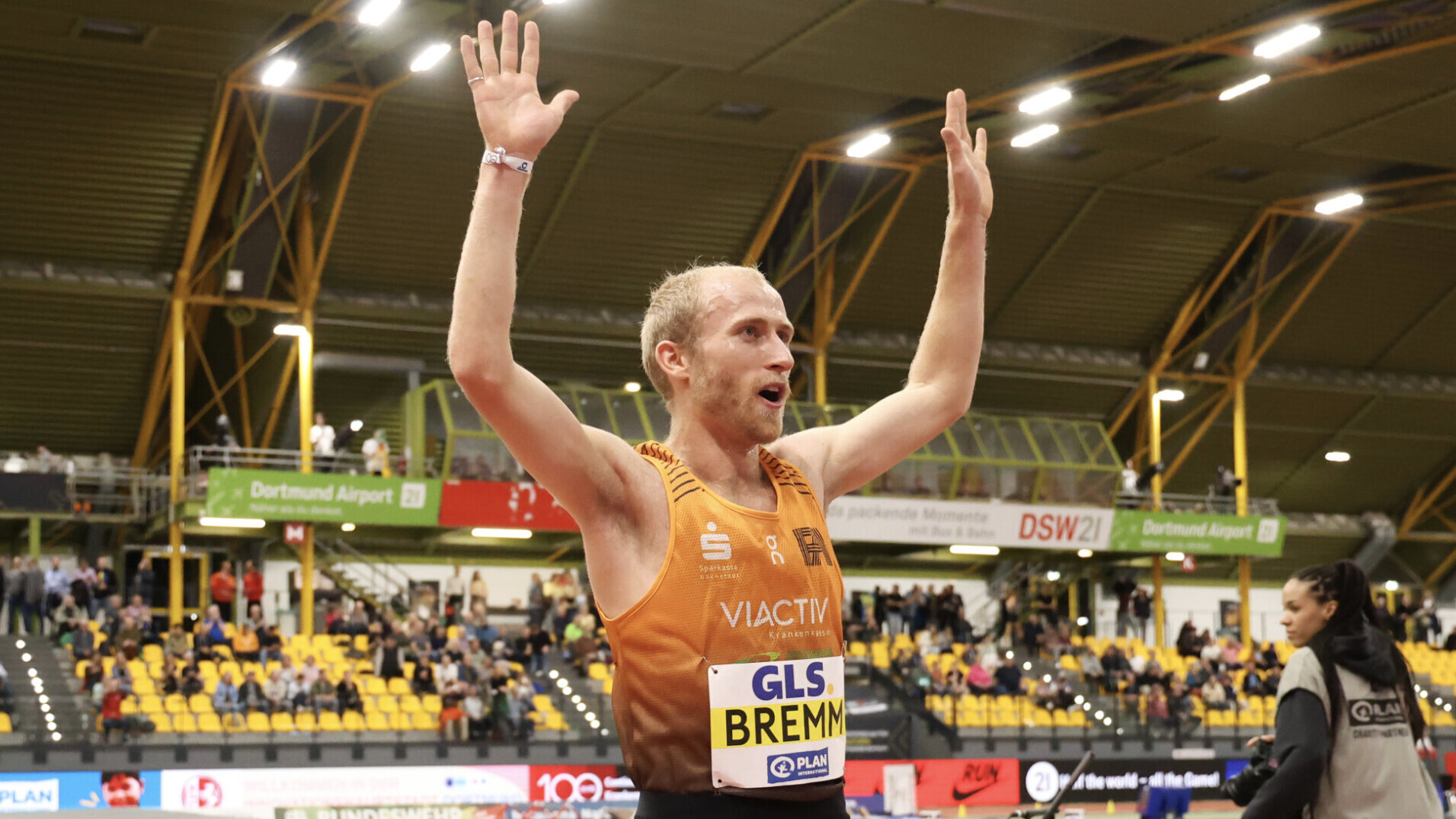 Der deutsche Läufer Florian Bremm jubelt in einer Halle und hebt dabei beide Hände über den Kopf.