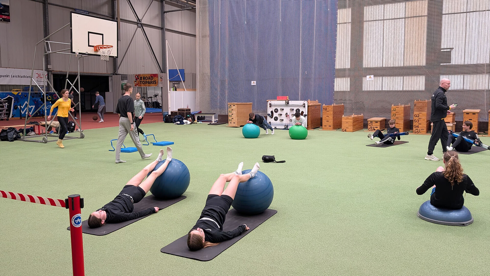 Sportlerinnen und Sportler beim Training mit Matten und Bällen