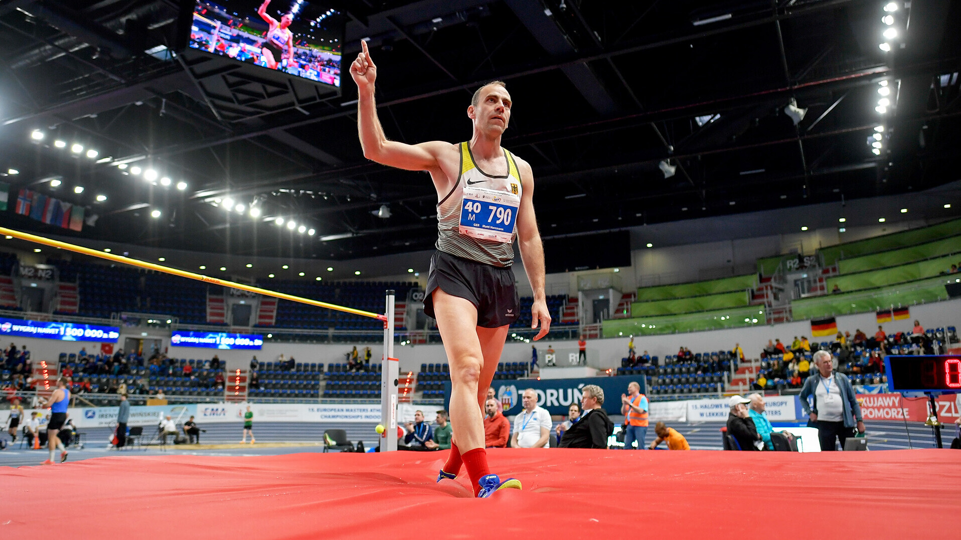 Matti Herrmann mit gerecktem Zeigefinger auf der Hochsprungmatte