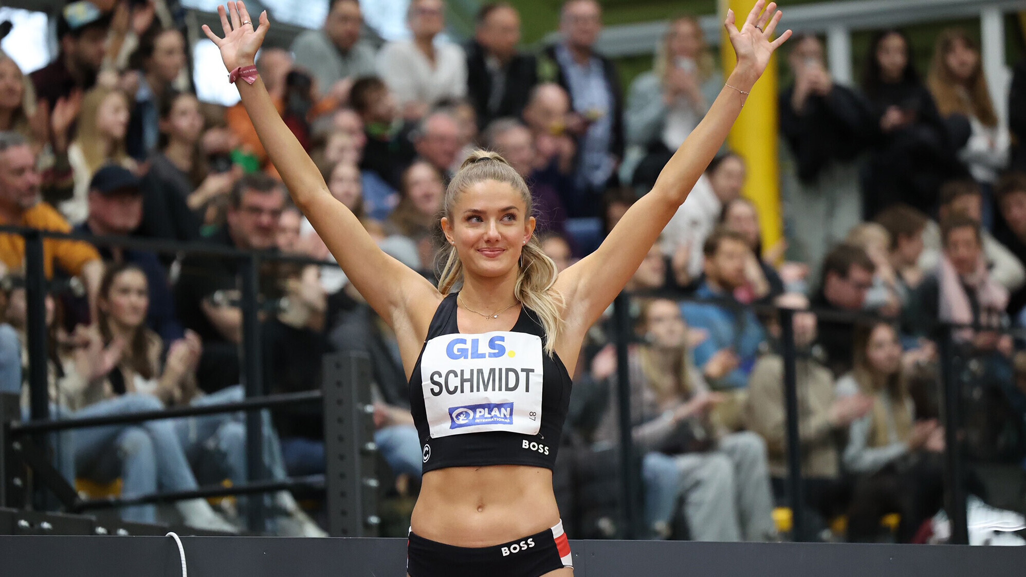 Alica Schmidt, im Trikot auf der Laufbahn stehend, winkt mit beiden Armen