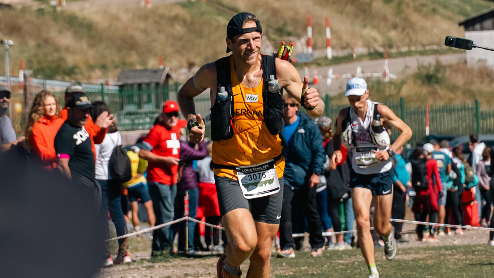 Manuel Hartweg im Nationaltrikot, mit Stöcken und Weste am Berg