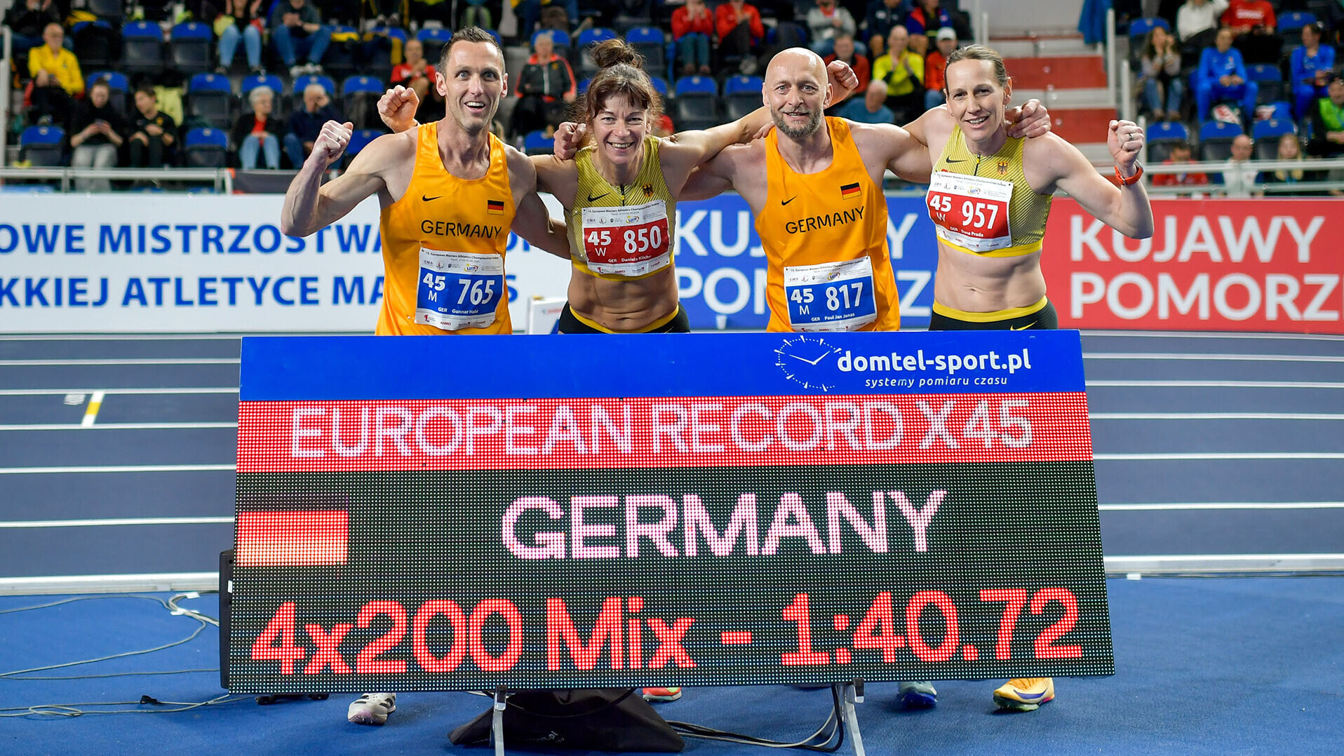 Vier Personen posieren hinter einer Anzeigetafel, auf der steht "European Record X45 Germany 4x200 Mx 1:40,72" 