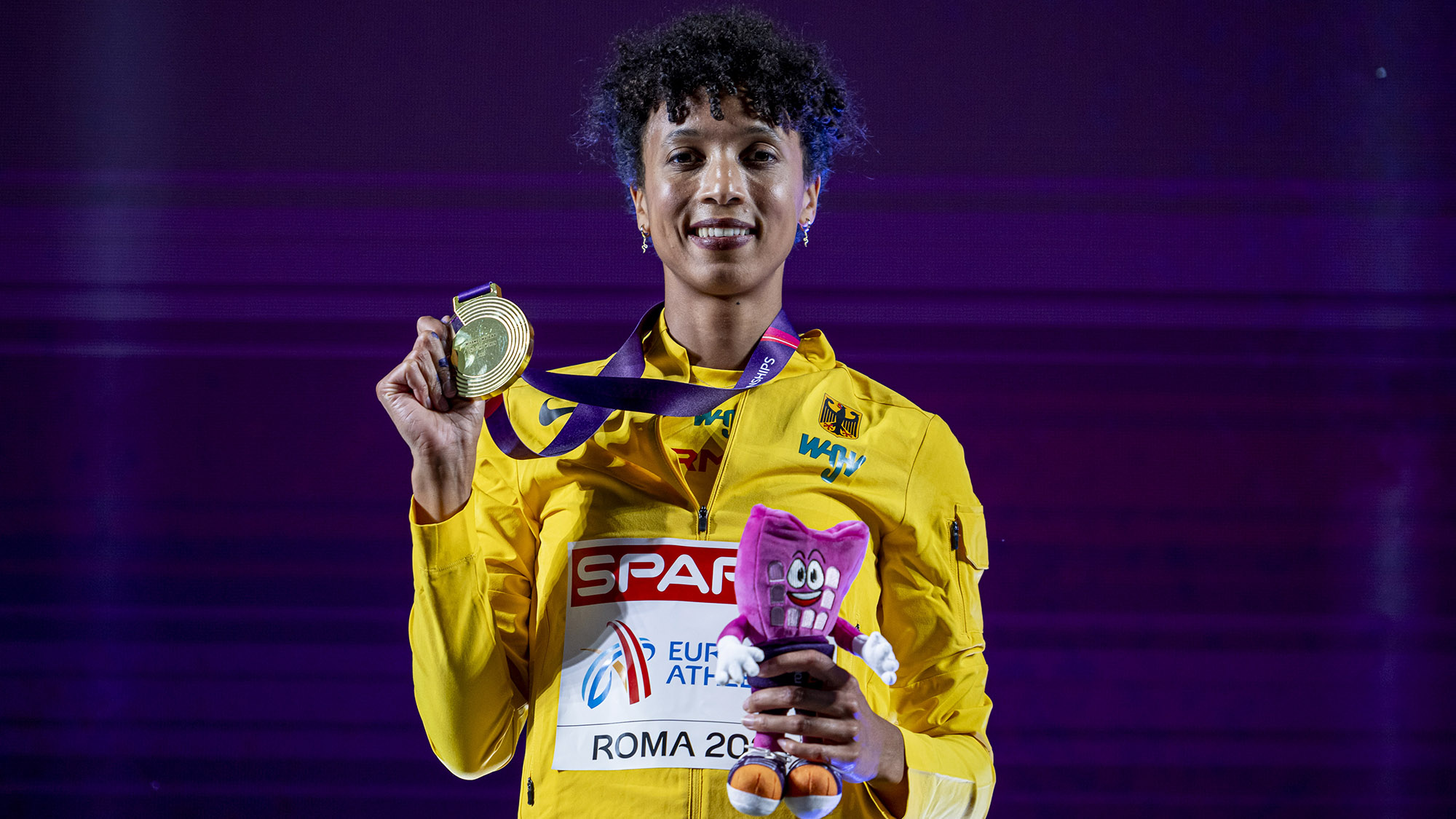 Malaika Mihambo präsentiert im gelben Siegerehrungsdress ihre Goldmedaille